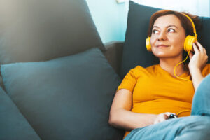 Mature woman on couch listening to music