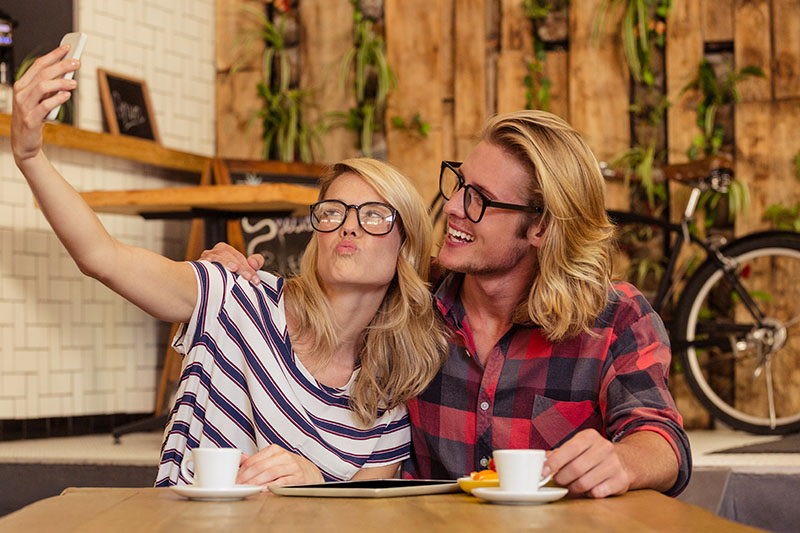 Couple in matching glasses taking a cafe selfie