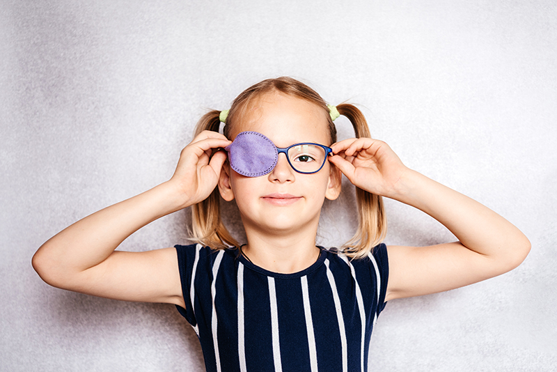 Young smiling girl with eye patch and glasses