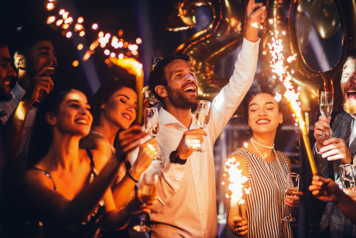 Group of friends celebrating with drinks and fireworks