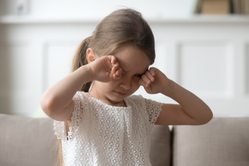 Unhappy little girl rubbing her eyes