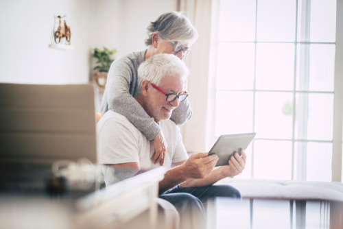 Senior couple smiling looking at a tablet