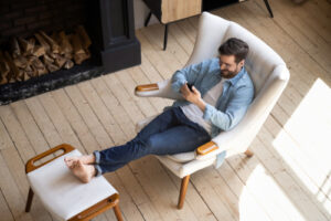 man sitting on chair while using cell phone