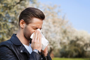 man with allergies using tissue