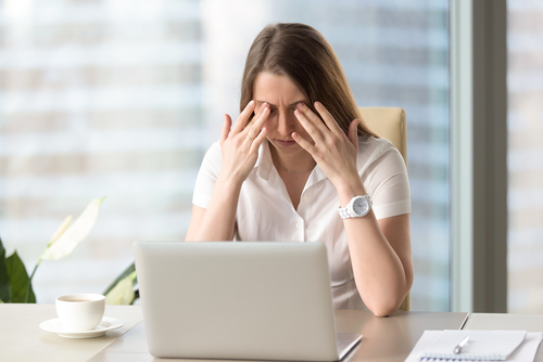 Business woman in office setting rubbing her eyes