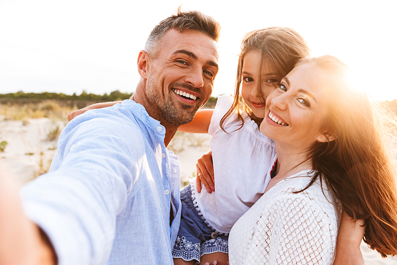 Happy family spending good time at the beach together, taking selfie